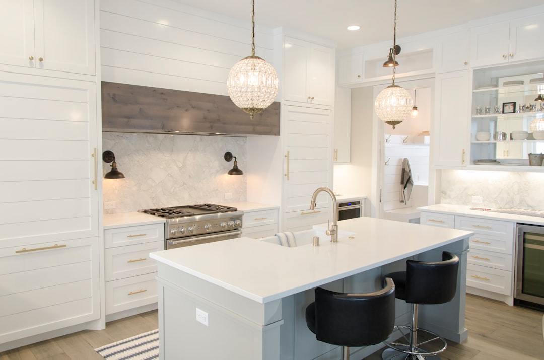 Modern kitchen with white cabinets, marble backsplash, and hanging lights.